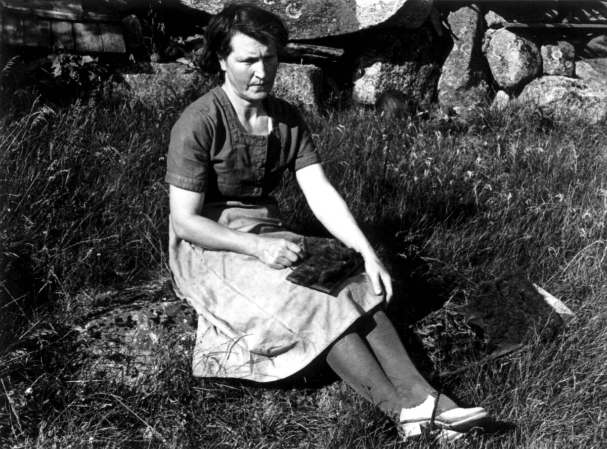 Maria Høydal sitter ute og karder ullfiller etter at de har vært stampet. Kvinesdal 1941.