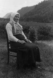 Kari Hodne, født i bortelid 1871. Hun sitter på en stol, sko