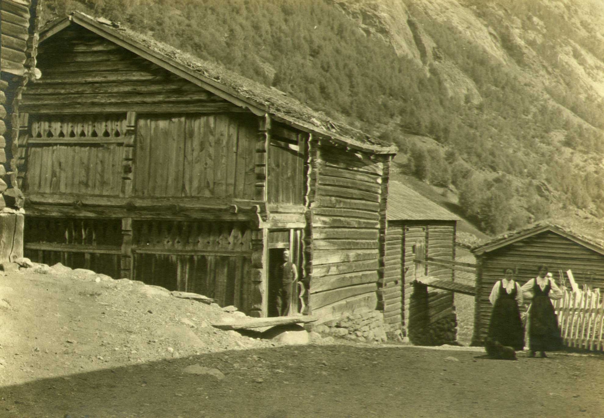 Stall, Sulheim, Bøverdalen, Lom, Oppland. To kvinner og mann i forgrunnen. Fotografert 1915.