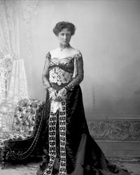 Portrett, kvinne i mørk kjole med chiffonermer. Fru G Dahl.