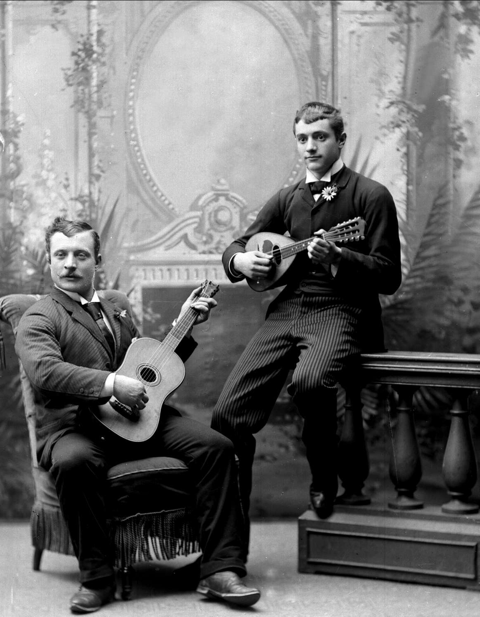 Gruppeportrett, to herrer spiller duett, gitar og mandolin. Gazgani.
