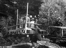 Gruppe mennesker stående på plattform/brygge i tre. Fjell/be