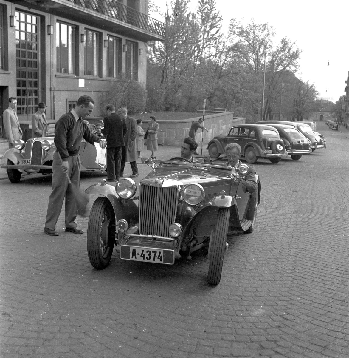 K.N.A. arrangerer rebusløp, billøp, mai 1952. Biler foran bygning.