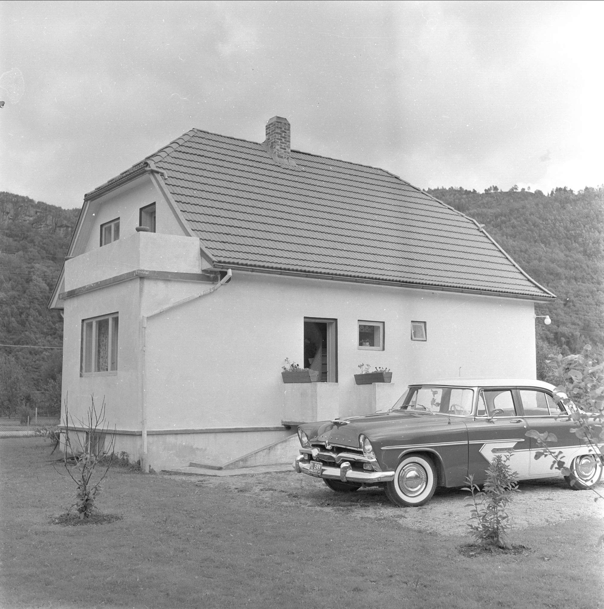 Kvinesdal, Vest-Agder, august 1958. Norskamerikanere i Kvinesdal. Bil foran hus.