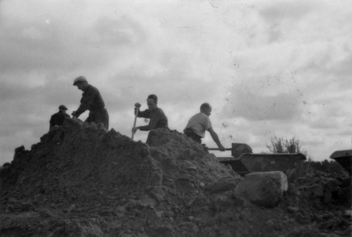 Idrottsplatsen på F 2 Roslagens flygflottilj byggs, 1943. Civilanställda tjänstemän i arbete med grävning. Människor och maskiner i arbete med grävning.