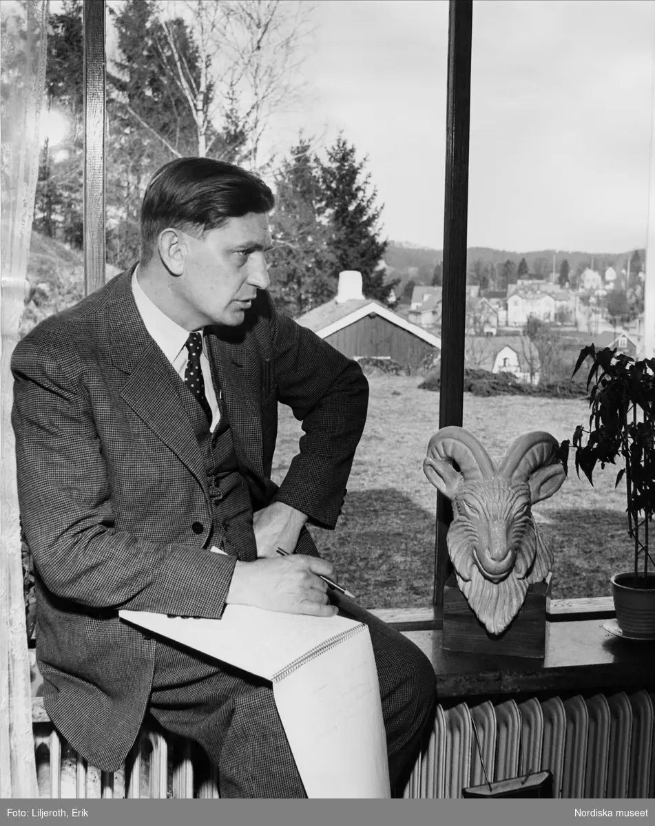Författaren Sven Edvin Salje sitter på fönsterkarmen med ett anteckningsblock i knäet