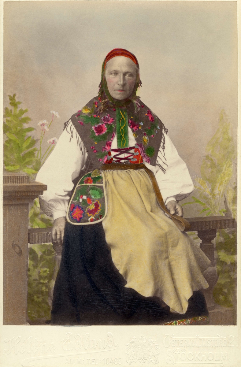 "Floda utställningen 1897."  En kvinna poserar i en folkdräkt med skinnförkläde
