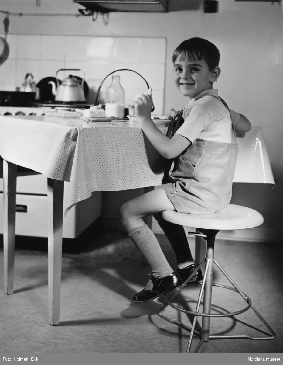 Reklambild för NKs arbetsstol. Pojke sitter på pall vid köksbord.