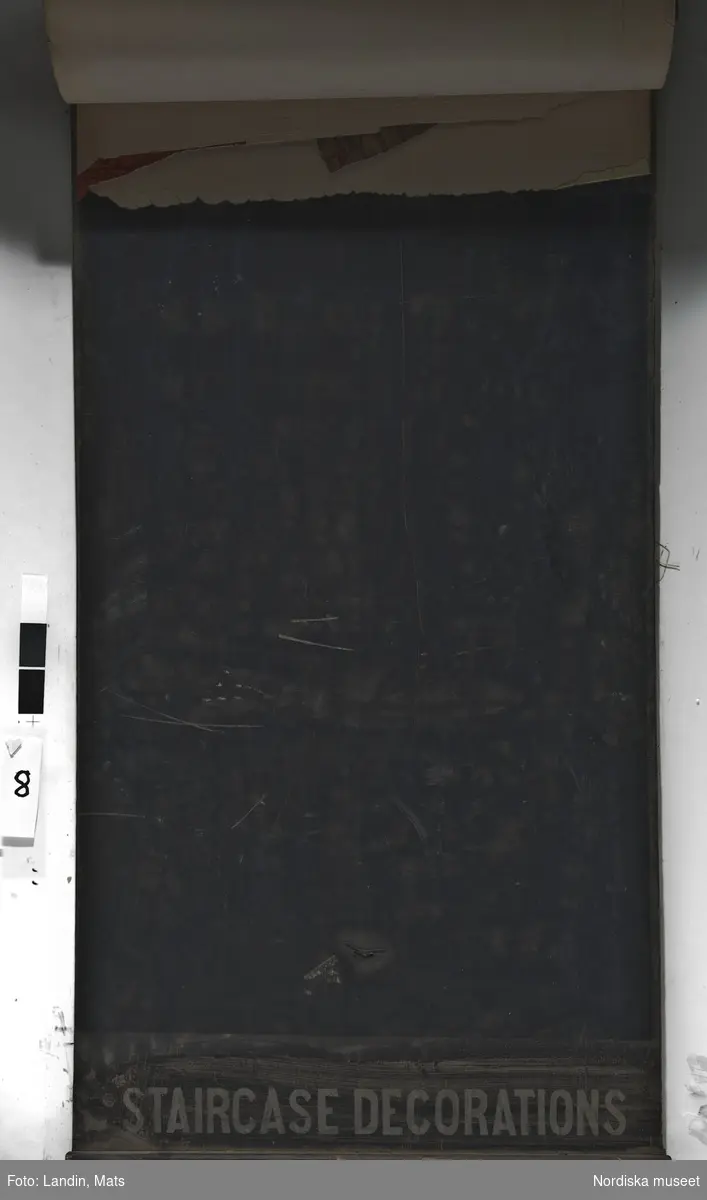 Tapetprov. Skyltställ, innehåller drygt 100 tapetprover och tapetbårder avsedda för trappuppgångar från tapetfabriken Jeffrey & Co., Storbritannien. Här finns tapeter av mer geometrisk karaktär, avsedda för rummets bröstning samkomponerade med svepande mönster avsedda för väggen ovanför. 1800-talets andra häft.