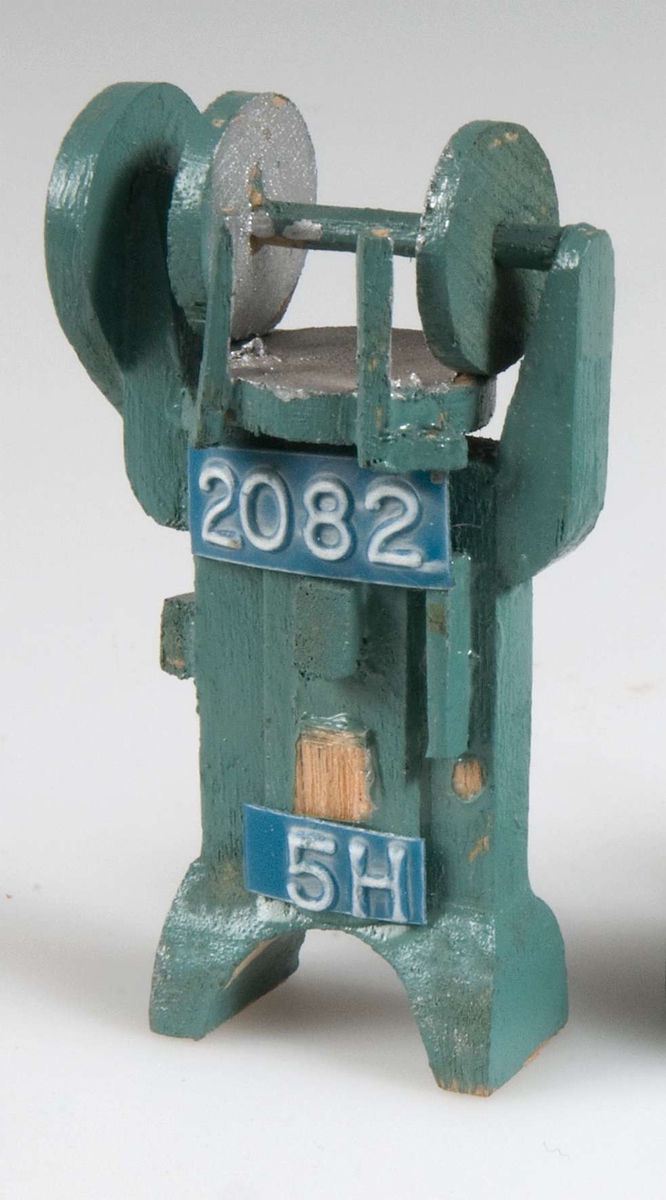 Liten maskinmodell av trä målad ljusblå med detaljer i silver märkt med blåvita denamoremsor med nr 2082 och 5 H.
