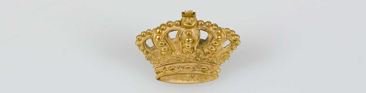 Kunglig krona av gul metall, har varit fäst på ramen till fotografiet UM37397a.