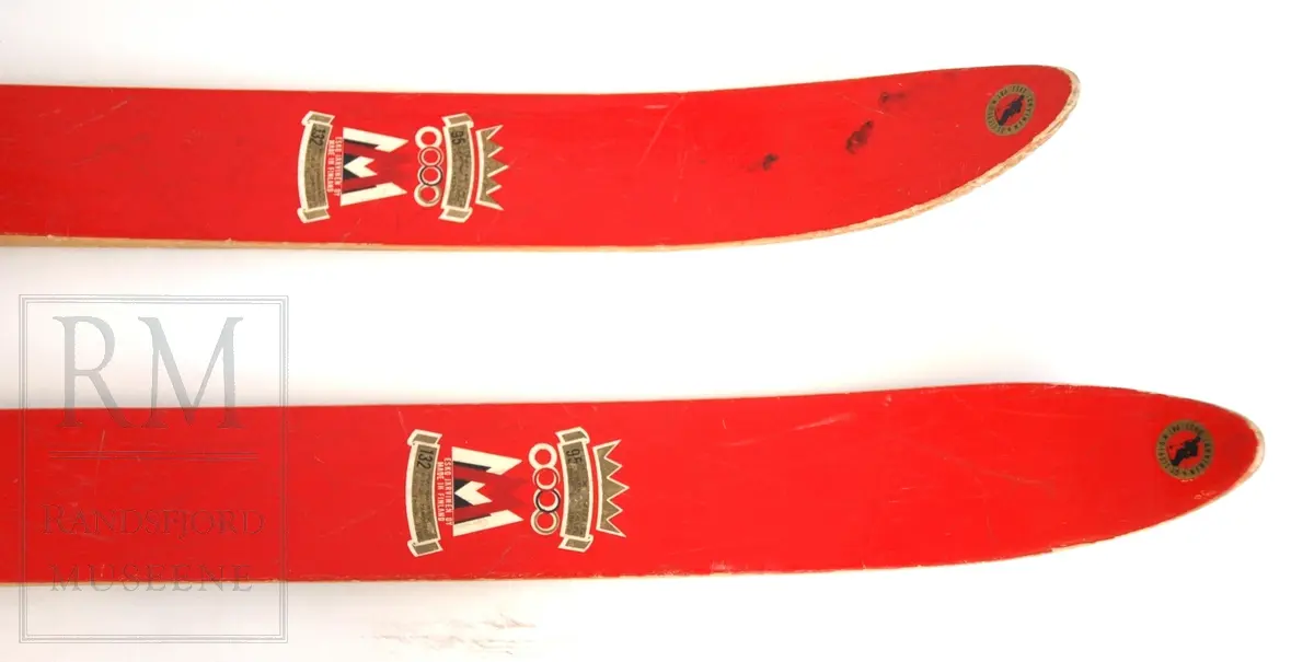 Røde ski med blå kalosjebindinger i lær