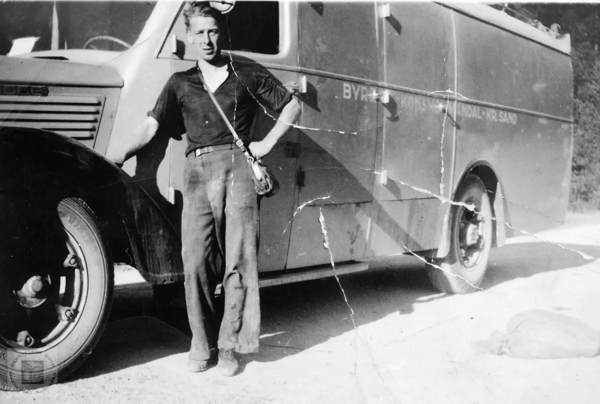 Sjåfør Gustav Hårtveit klar til avgang fra Byremo.
Bilen er en Dodge, årsmodell 1937-38. (Jfr. bokstavene "DGE" på siden av panseret.)