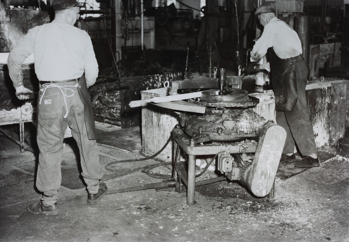 To arbeidere bøyer tinner for fjørharv og herder disse etterpå i den gamle smia i 1895-bygget, t.v. Magne Kyllingstad i en Øglænd-bukse