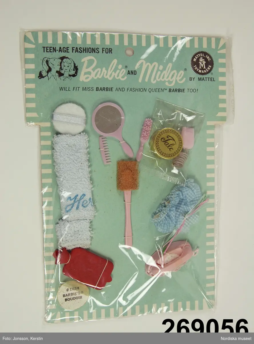 Inventering Sesam 1996-1999:
L 20  B 15 (cm)
Toalettillbehör till Barbie/Midgedocka, "Barbie's boudoir", i originalförpackning. Innehåller blå frott¿handduk och duschmössa,  kam, borste, spegel, badsvamp med handtag, rakapparat, och telefon av rosa plast, ask med talk, pudervippa och värmeflaska av rött gummi. 
Föremålen är fastsydda på grönblått pappark, täckt med plastfilm, text och bild i svart tryck. Modekatalog fasttejpad på baksidan.
Midge är dockan Barbie's bästa vän. 
Anna Womack feb. 1997
