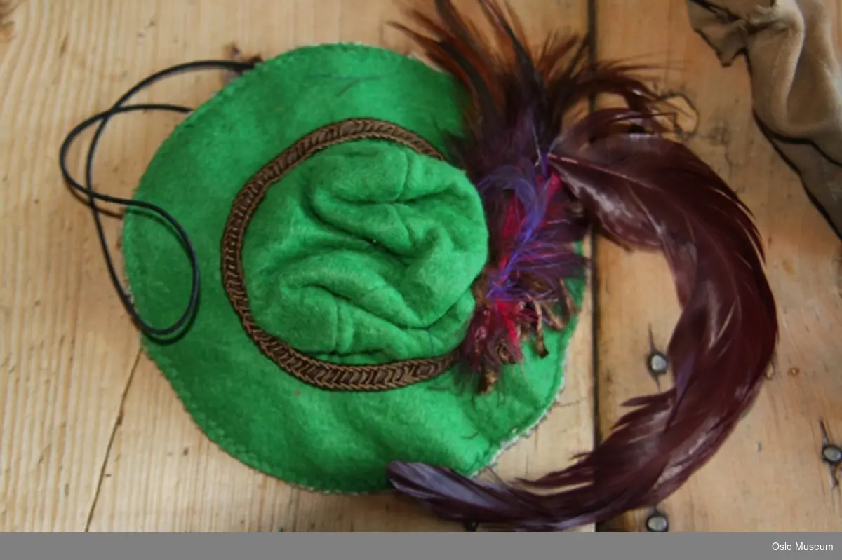 Filt-trukket hode med hatt i grønn filt med rosa tråd med blomster knyttet rundt bremmen.
