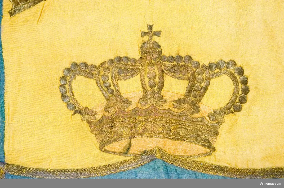 Blå botten med gult kors. I guld broderat: "KONGL. NORRA SKÅNSKA INFri Rt Ista BAT." Stång av vitmålad furu, med spets. Spets har Carl XIV Johans namnchiffer.