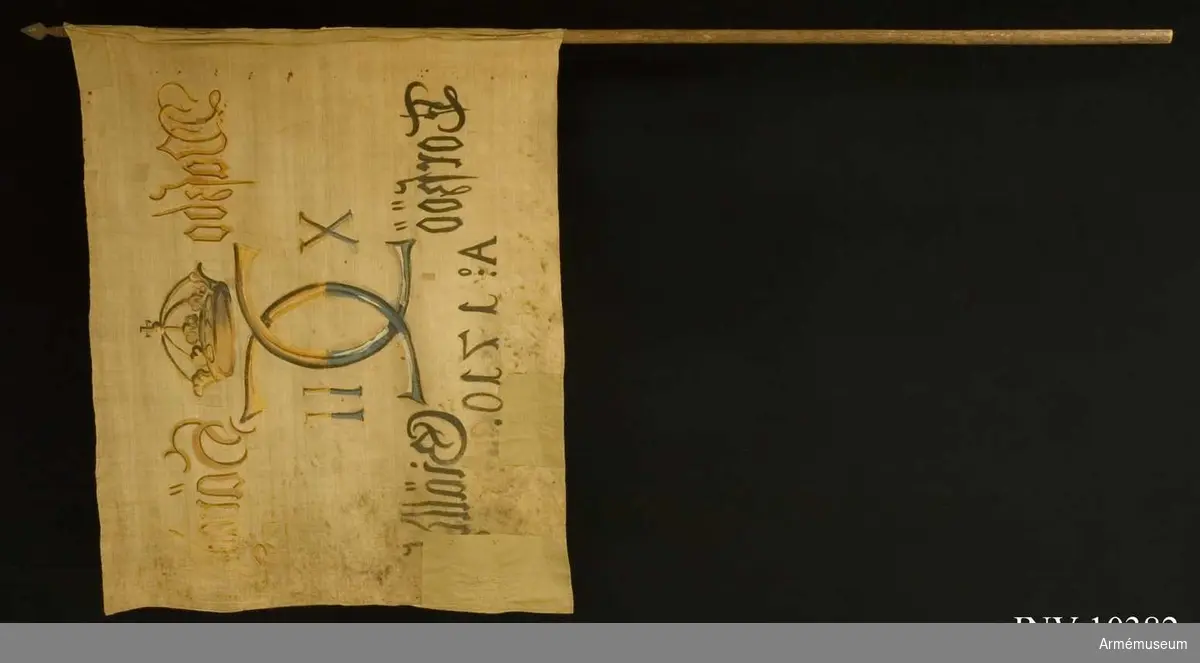 Grupp B I.

Fanduk av lärft, hopsydd av två våder, med målade emblem, lika på båda sidor, Karl XII:s namnchiffer, av sluten krona krönt spegelmonogram, avdelande siffrorna X - II. På ömse sidor om namnchiffret: Waszbo Häradh - Torszöö Giälldh och därunder A:o 1710. Målningen på övre halvan gul och brun, på nedre halvan blå  med svart skuggning. Fastspikad direkt på stången utan lindning  och rem. Stång av furu, brunmålad.Spets av järn, bladet platt, spjutlikt i ett stycke med kort holk, varifrån utgår korta skenor.