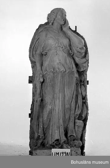 Gipsförlaga till skulptur föreställande stående kvinna "Gudinna" som sjunger eller ropar. Klädd, i lång tunn och veckrik dräkt och hållande ett instrument? i höger hand. Står på en 12 cm hög sockel. Statyns överdel vitgrå och den nedre delen gulbrun. Uppbyggd på en stomme av trä och fylld ett stråmaterial samt juteväv.
På skulpturens sockel står det "J.A. Wetterlund 1922".
Dnr. 20-967/80.
Där står antecknat: Ca 30 st gipsfigurer och verktyg som gåva till BM.
Se även UM19236 -19250.

Förlaga till skulptur/allegorisk figur i granit placerade i runda nischer på byggnaden Göta källare, Hotellplatsen, Göteborg. Utförda 1922.
Fyra olika skulpturer finns varav vtvå av förlagorna ingår i denna gåva.

Konstnären har gjort förlagan till lejonen i brons framför universitetsbyggnaden vid Vasaplatsen, Göteborg.

Litteratur:
Se Svenskt konstnärslexikon del V för att få ytterligare upplysningar om hans verk.
I Västgötagenealogen 1992:4 finns artikeln "Johan Axel Wetterlund - slottsskulptören från Västergötland", Stieg-Erland Dagman, Habo.