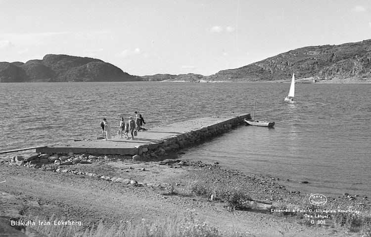 Enligt AB Flygtrafik Bengtsfors: "Lökeberg sjön m. bryggan Bohuslän".
Enligt text på fotot: "Blåkulla från Lökeberg".
