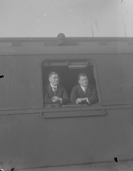 Enl. text i blå bok: "Två män i tågfönster."