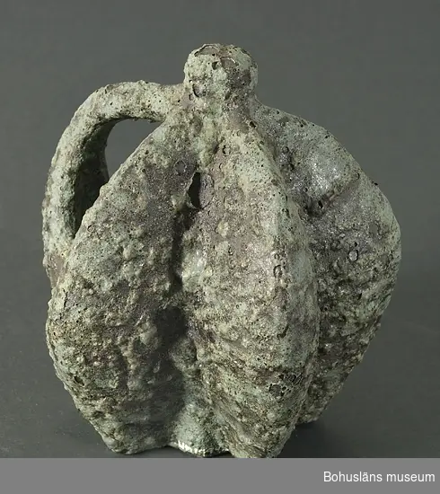 Skulptur "Äppelskrott" med grön lavaglasyr.
Kompletterande upplysningar se UM019982