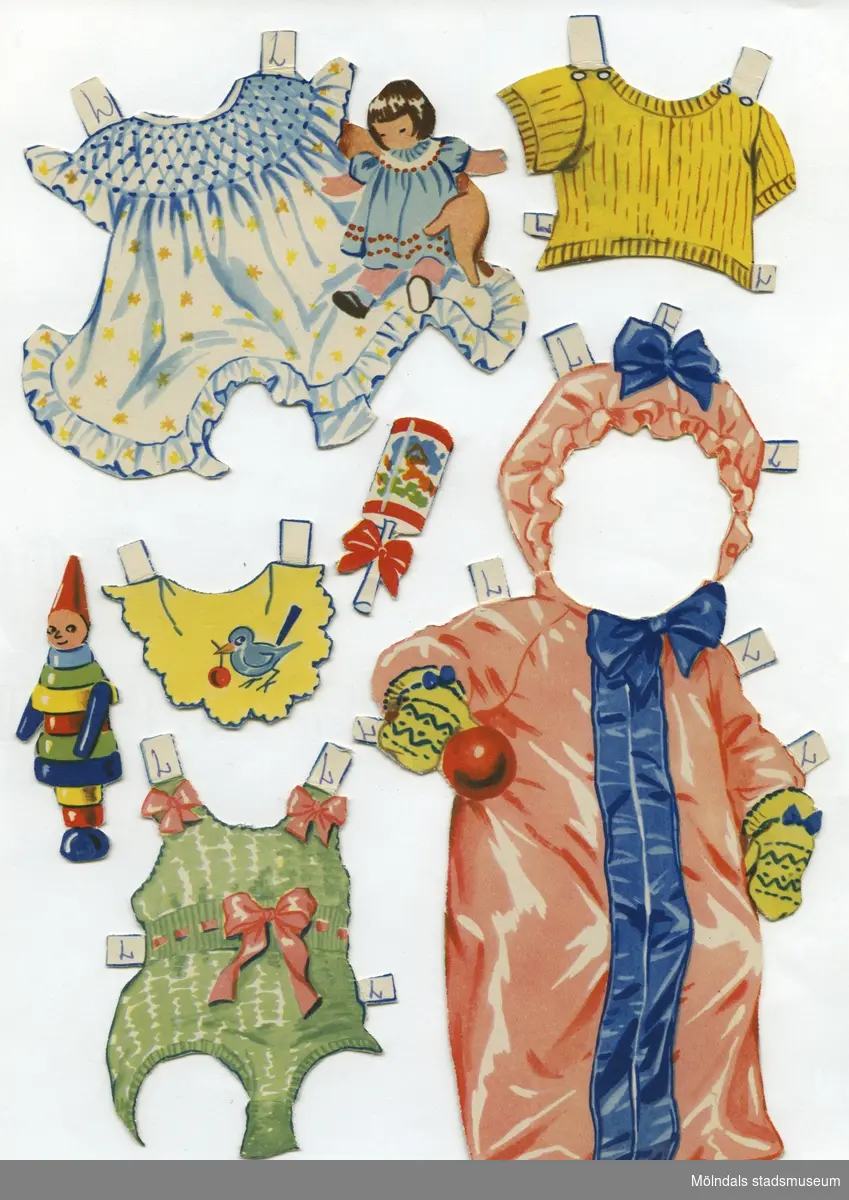 Pappdocka med kläder och tillbehör. Docka och kläder är märkta "Lillan" på baksidan - dockans namn. Dockan föreställer en baby, med blont hår och blå ögon, iklädd rosettprydda underbyxor. Garderoben består av en liten tröja, tre lekdräkter, tre klänningar, skor, mössor, samt ytterkläder. Dockan har också tillbehör, såsom potta, hårborste och leksaker. Dockan förvaras, tillsammans med "Lena" (MM 04636), i ett ihopvikt silkespapper med texten "Ljungsko, Kvalitetsko".