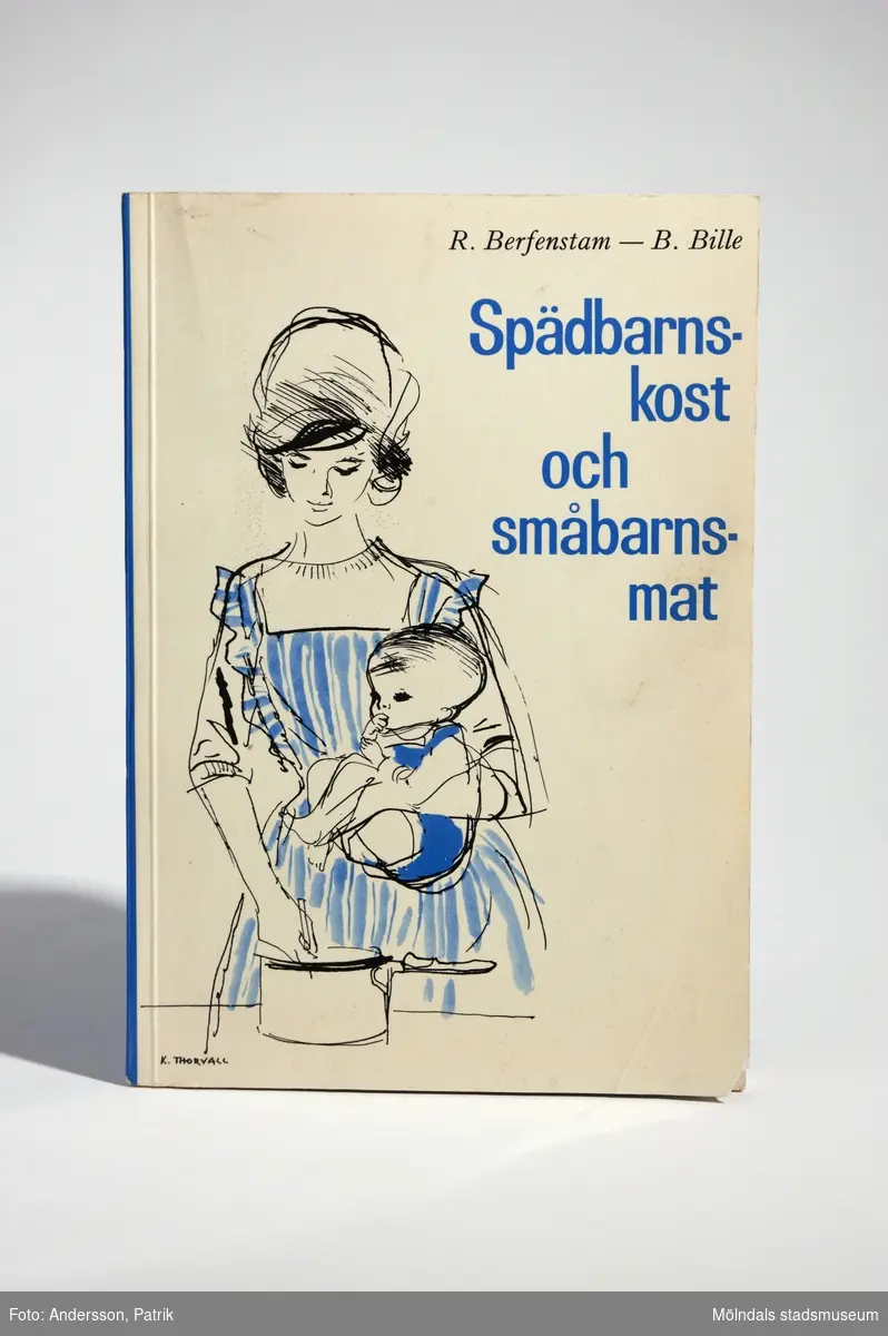 Handbok - "spädbarnskost och småbarnsmat" (skrift nr 39), 2:a upplagan, utgiven 1965 av Socialmedicinska barnavårdsdelegationen. Författare: Ragnar Berfenstam och Bo Bille i samarbete med Ingrid Frelin, Siri Kivilinna och Birgitta Melin. Tryckeri: Almqvist & Wiksells Boktryckeri AB, Uppsala 1965.Boken har mjuka pärmar. Framsidan är vit bakgrund med en tecknad bild på en mamma vid spisen och ett barn på armen. Bilden går i färgerna blå, vit och svart. Bredvid bilden står bokens namn tryckt med blå text.Bokens baksida är blå. Där står bokens pris: "Pris kr. 5:50", tryckt med vit text.Boken är en handledning med råd och recept på barnmat.Omslag och teckningar: Kerstin ThorvallFotografier: Erland SköllegårdVinjetter: Dick Hallström MåttLängd: 210 mm, Bredd: 147 mm, Höjd: 7 mm