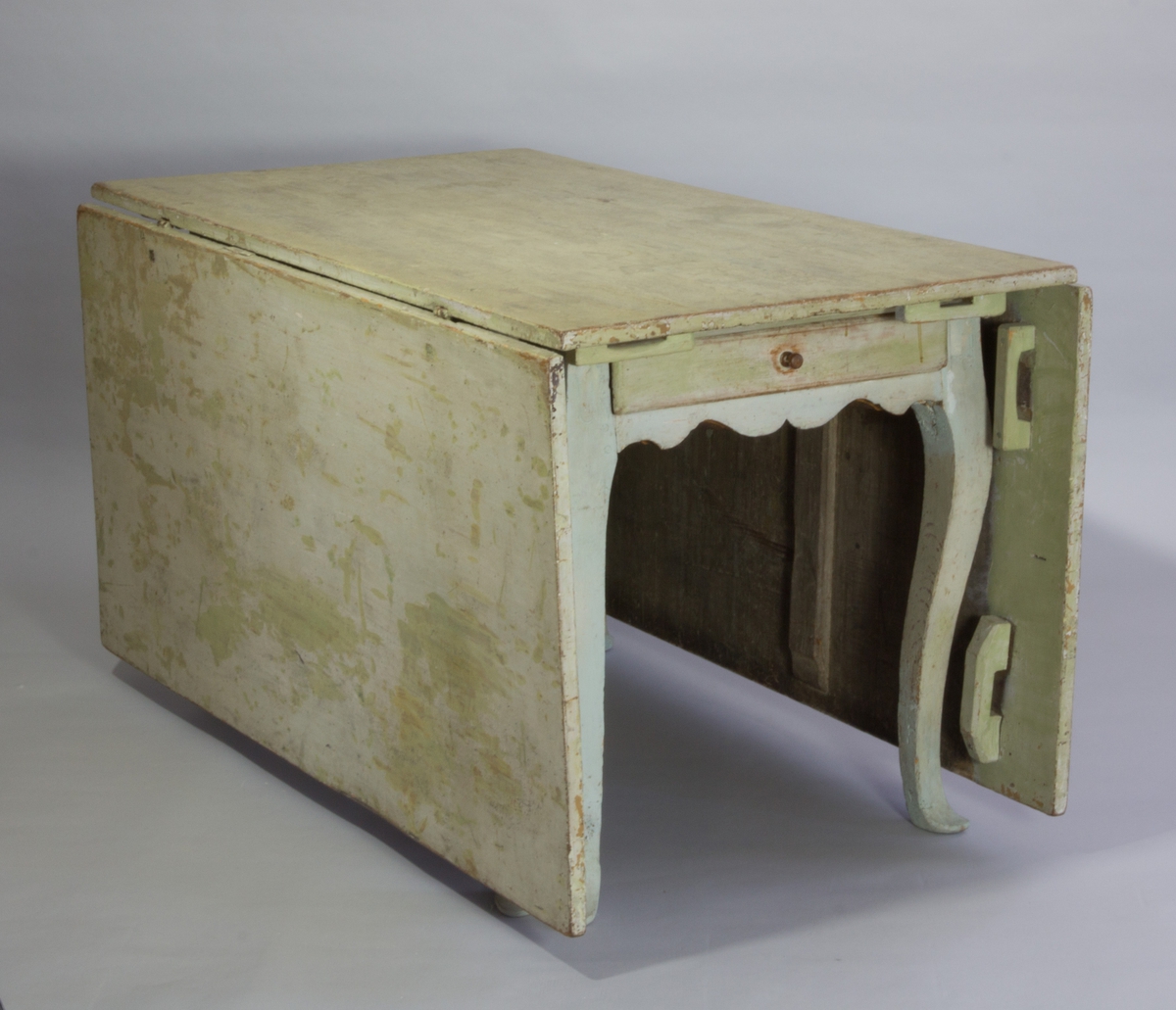 Slagbord av målat trä med två uppfällbara flygelskivor och med svängda ben med profilerade avslut. Sarg med låda.