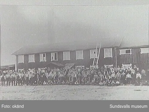 En grupp arbetare framför en byggnad på Myrnäs ångsåg.