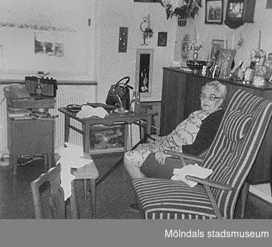 Anna Bengtsson sitter i ett rum på Brattåshemmet år 1980. Från en fotodokumentation 1985-86 av Staffan Bjerrhede och Birgitta Lans. Ålderdomshemmet Brattåshemmet låg på Brattåsvägen 3 el. 4 och var i bruk mellan 1955 och 1986.