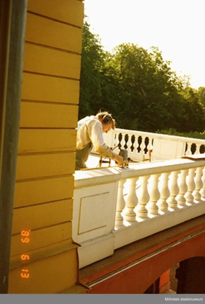 En man står och slipar räcket på balkongen.