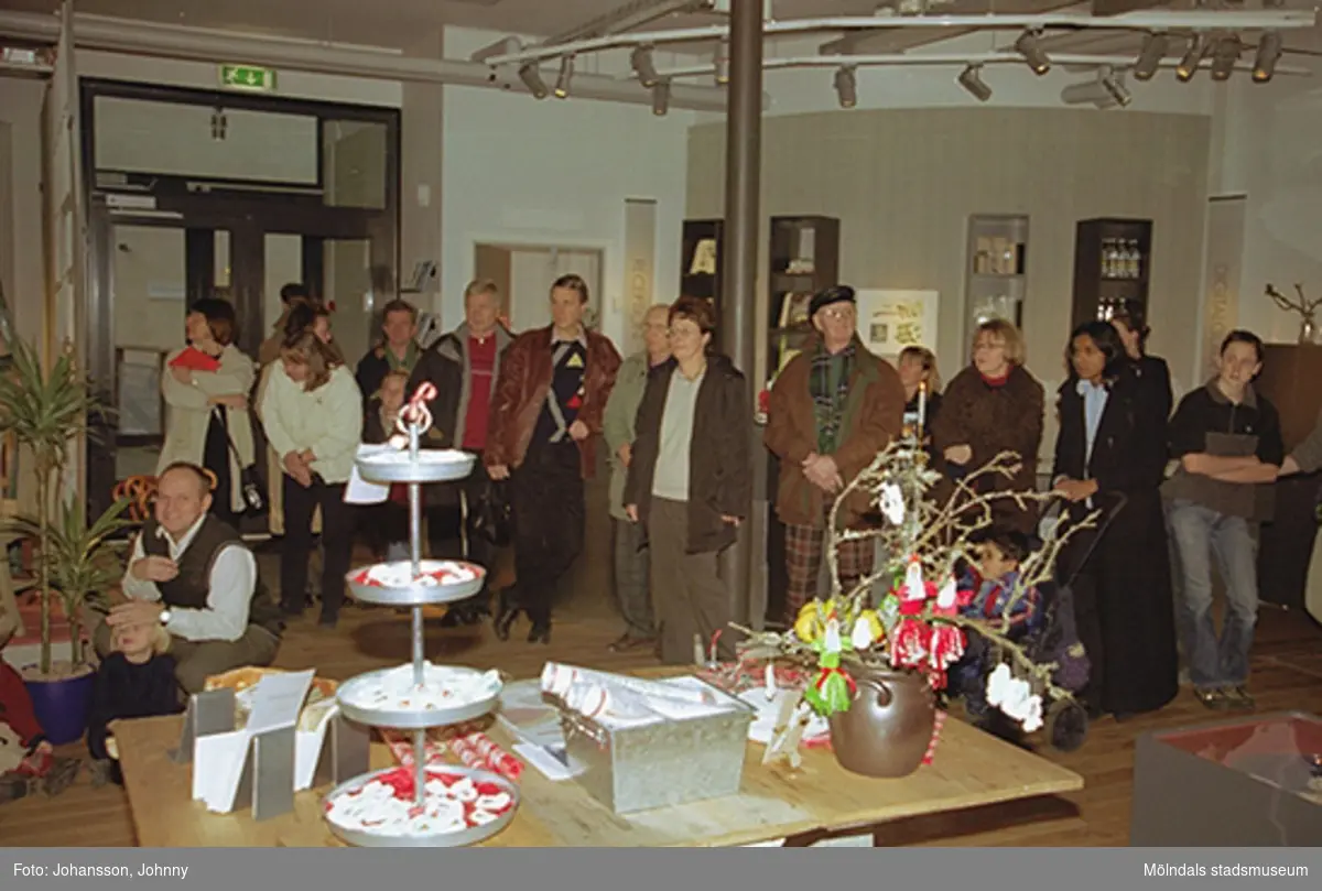 Besökare tittar på när Opus sångkör sjunger på Mölndals museum 2002-12-15.
Tomteutställningen: 30/11-02 - 1/1-03.