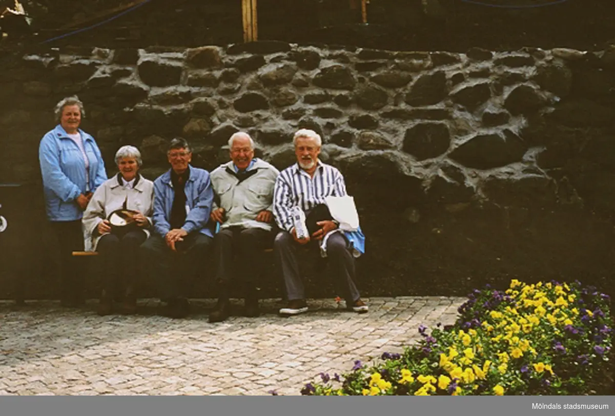 Gatlyktan invigs på Kvarnbydagen 25/4 1993. Fem personer står vid eller sitter på en bänk framför en mur vid Lyktplatsen i Kvarnbyn. Fjärde person från vänster är Vigon Olsson och till höger om honom sitter Sven Johnson.