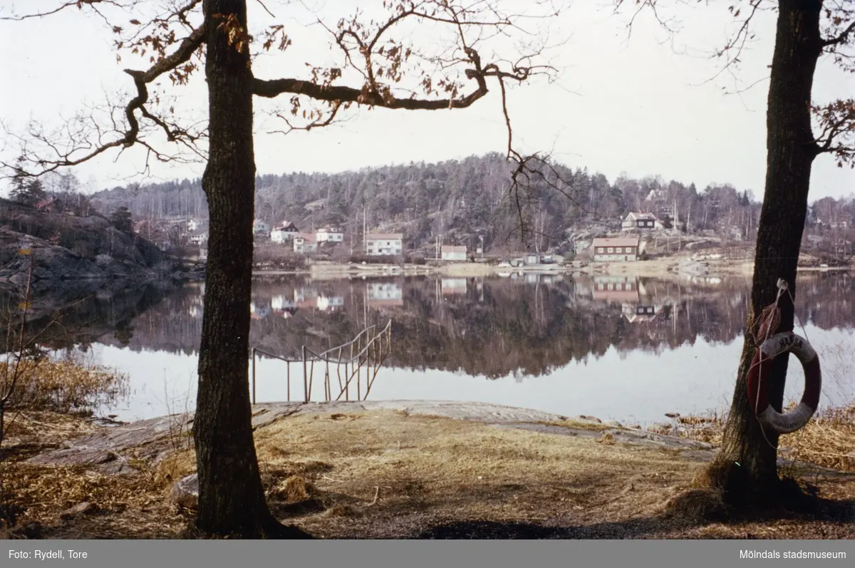 Vy från handikappbadplatsen vid Hästehagen i Gunnebo över Rådasjön i Mölndal på 1970-talet. På andra sidan sjön ses bebyggelse i Helenevik.