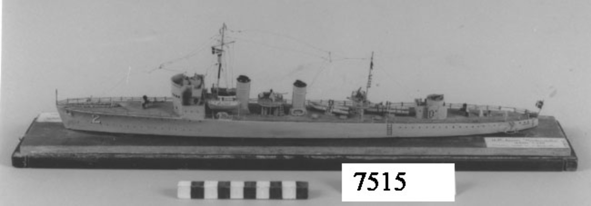 Fartygsmodell av H.M. jagaren Nordenskjöld inom glas på platta av trä. Gråmålad med ljusbrunt däck.