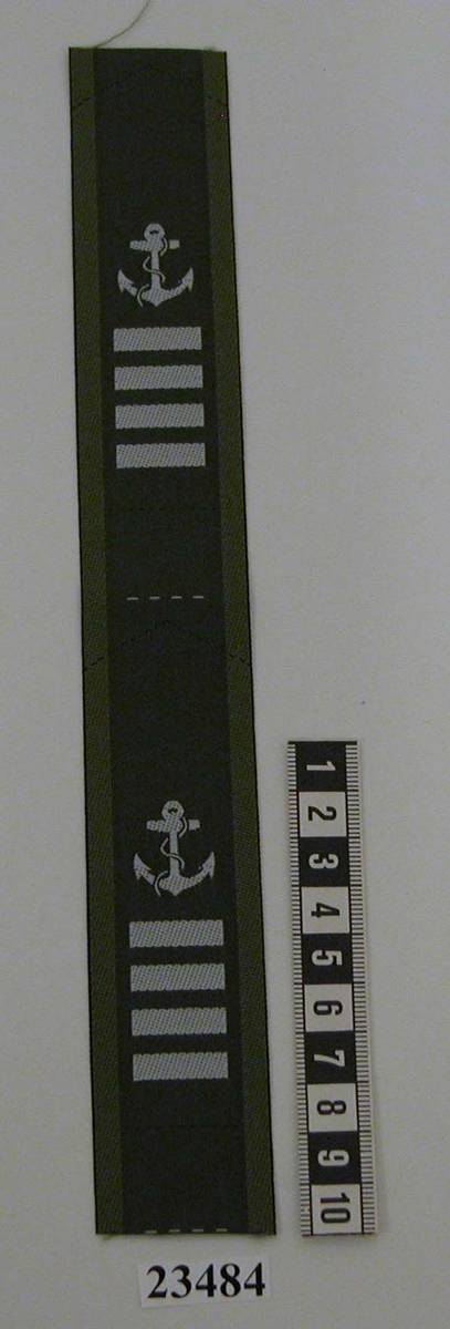 Tjänsteställningstecken (ett par ihopsytt men med markering för isärklippning) för överfurir för civilanställd personal i flottan. Beteckningen har samma utformning som gradbeteckningar men är invävd i vit färg på kragspegel m/58. Tecknet består av fyra stolpar 6 mm samt ovanför ett stockankare med tross. Ankaret är 20 mm högt.