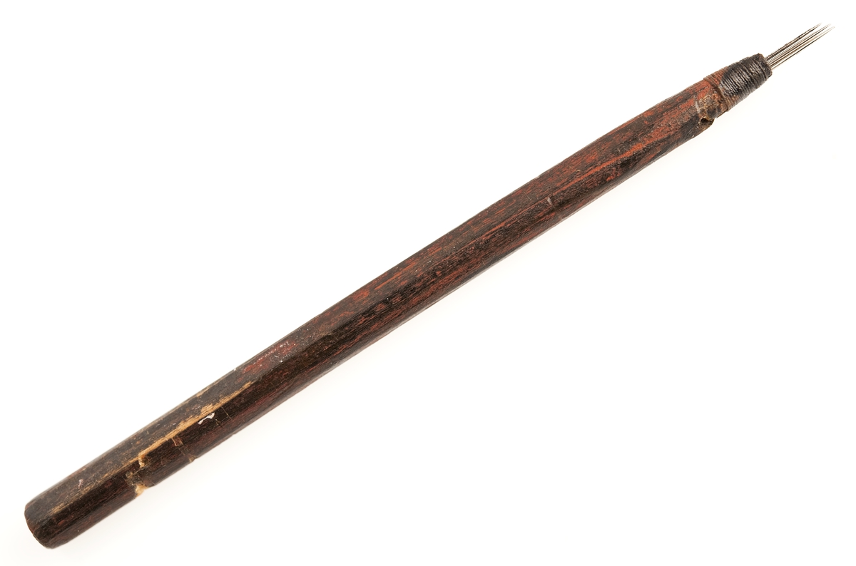 Tatueringsverktyg, skuggnål. Tre stycken synålar fästade vid ett skaft av trä. Inkom till museet 1934.
