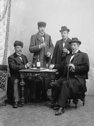 gruppe, menn4, hatter, frakker, bord, brennevinsflaske, glas