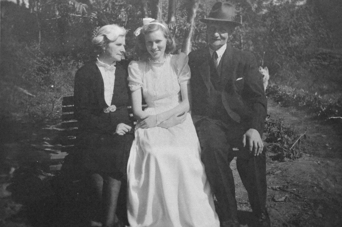 Gjertrud, Kari og Ole Aas, fotografert på en benk ute.