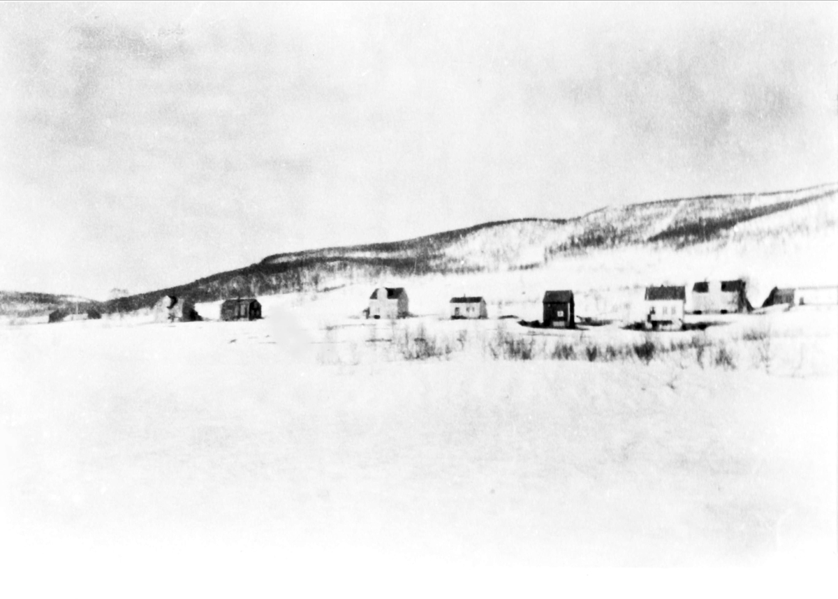 Vinterbilde av gårdene på Kilhus, fotografert fra nedersiden og oppover mot åsen.
