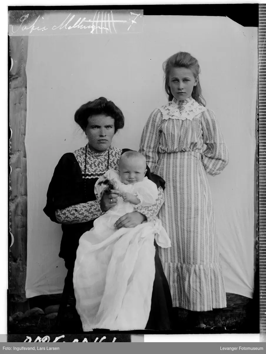 Gruppebilde av kvinne, jente og et spedbarn iført dåpskjole.