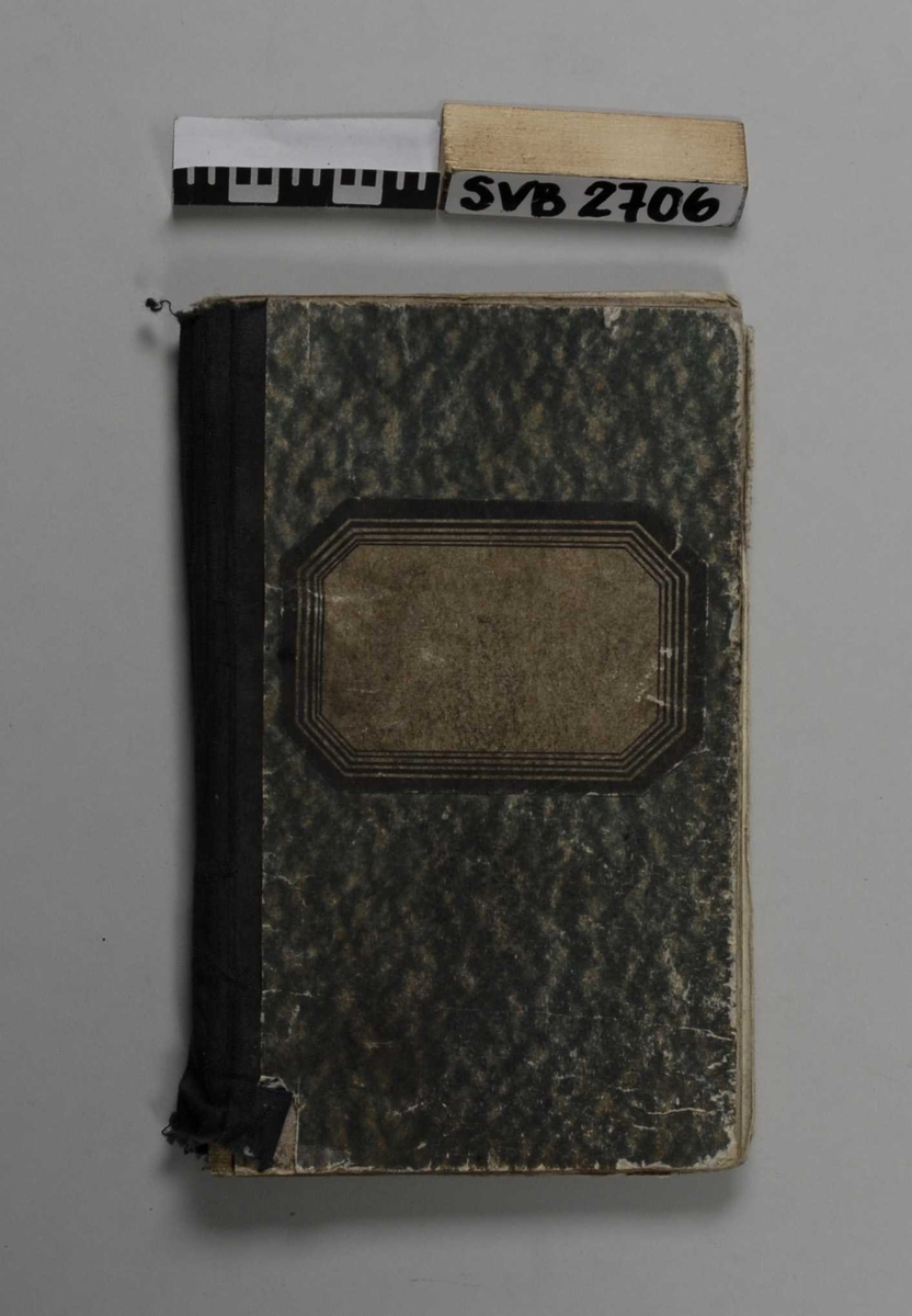 Notatbok i lommeformat med linjerte sider, håndskreven tekst. Grønnmelert omslag med rygg i sort tekstil. 8-kantet etikett i sort og hvitt på forsiden.