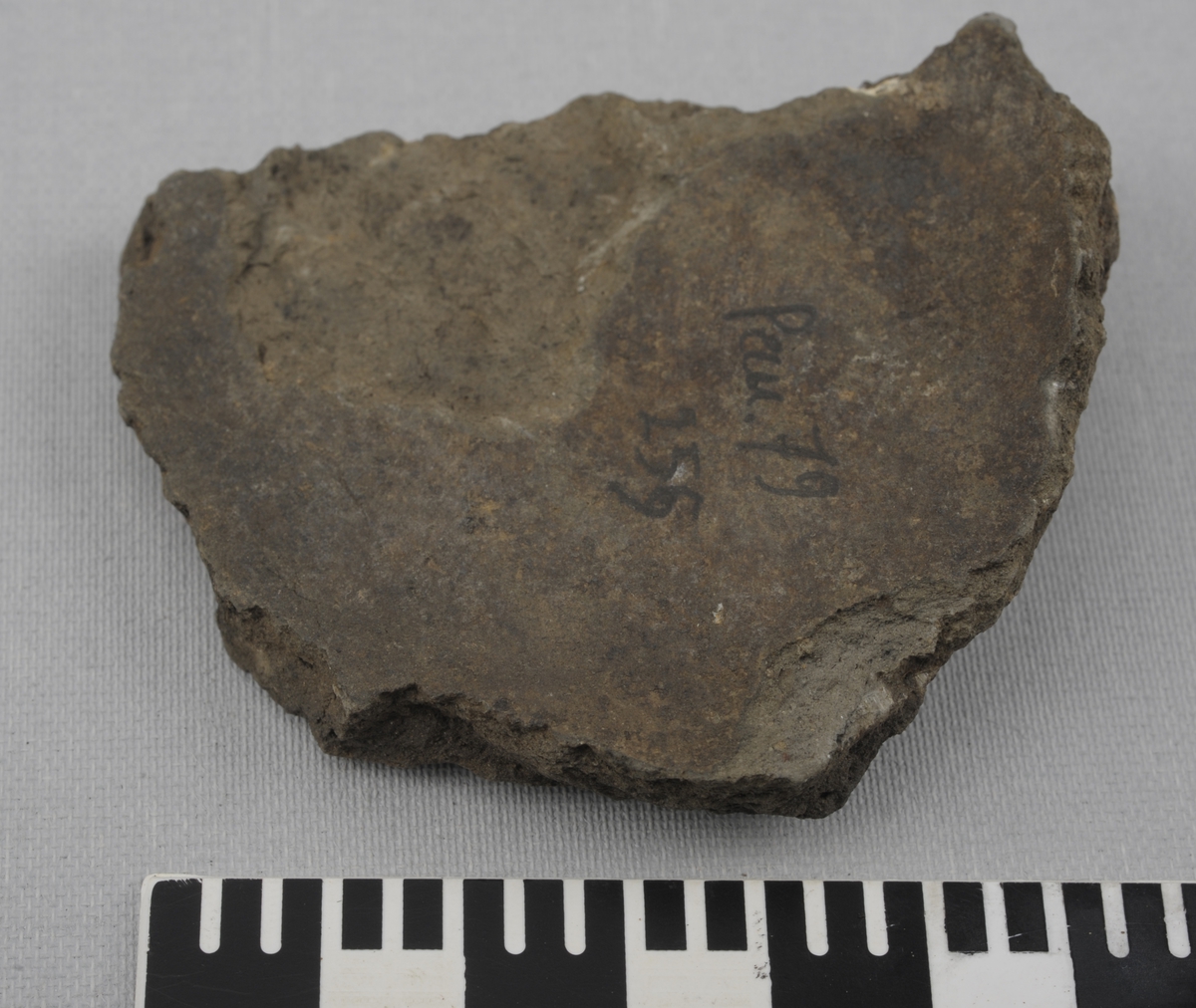 Skår av grå keramikk. Tynnere i den ene ende.