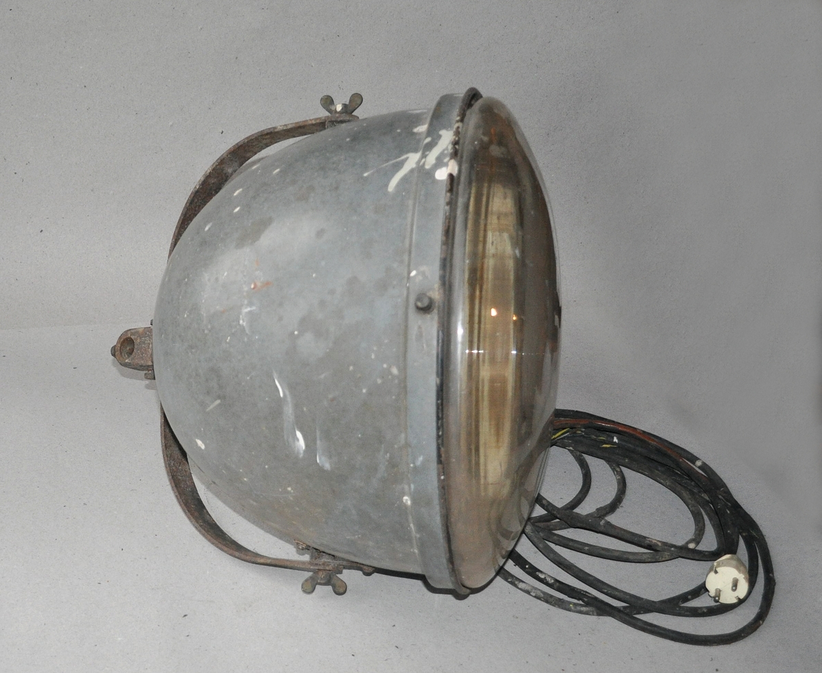 Lampe av emaljert jern, med glass og original lyspære.  Med ledning og støpsel, og jernbøyle til montering.
