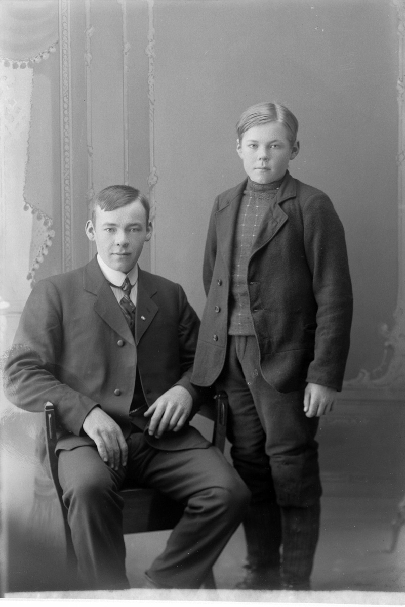 Studioportrett av ung mann ved siden av en gutt.