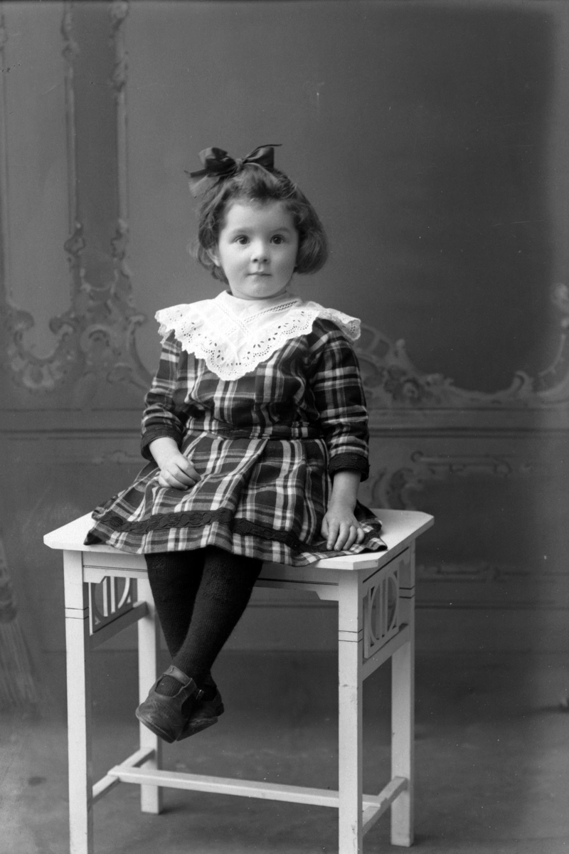 Studioportrett av en ung jente med sløyfe i håret.