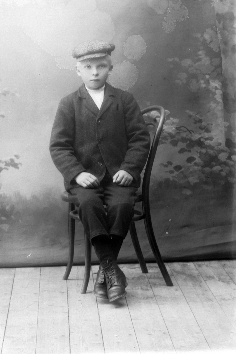 Studioportrett av en gutt som sitter på en stol.