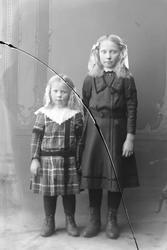 Studioportrett av to jenter i helfigur.