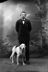 Studioportrett i helfigur av en gutt og en hund.